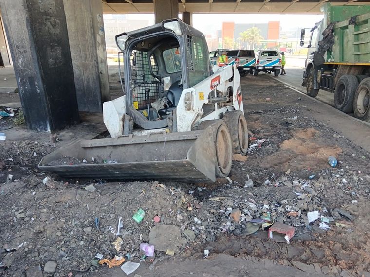 A wheel loader collecting trash under a bridge on Mooi Street